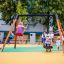 Kinder spielen auf einer Doppel Schaukel mit Babysitz und TS-Sitz auf einem Spielplatz.