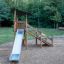 Elbrus Spielturm mit Rutsche aus Holz auf Spielplatz im Wald.