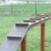 Hundeleiter mit Brücke aus Holz für Hunde auf grünem Rasen.