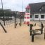 Leuchtturm Spielturm auf einem Spielplatz mit Hängebrücke und Kletternetzen.