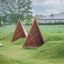 Tipi Spielhaus aus Holz auf einer grasbewachsenen Spielfläche im Freien.
