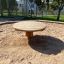 Runder Holztisch für Kinder auf einem Sandplatz, ideal für Außenspiele und Aktivitäten.