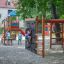 Kinder spielen auf einem bunten Spielturm mit Kletterwand und Schaukeln in einem Sandspielplatz.
