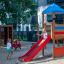 Kinder spielen auf einem farbenfrohen Spielplatz mit Rutsche und Spielturm.