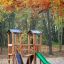 Holzspielplatz mit Rutsche Knirps II Spielturm im Herbstpark