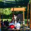 Picnic Unterstand aus Holz mit Sonnenschutznetz auf Spielplatz.