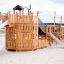 König Spielschiff mit Spiralrutsche aus Holz auf Sandspielplatz.