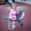 Kleines Mädchen spielt auf einem Walross-Federwippe auf einem Spielplatz.