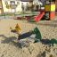 Doppelte Pferde Federwippe auf einem Spielplatz mit Sandboden.