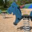 Blaue Pony II Federwippe auf Spielplatz im Sand.