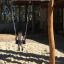 Kind schwingt auf Doppel Schaukel Robinie auf einem Spielplatz im Freien.