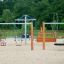 Doppel Schaukel Robinie und Spielplatzgeräte auf Sandboden in einem Park.