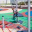 Kind klettert auf einem Netz der Kletterkombination Seestern auf einem Spielplatz.