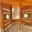 Innenansicht des hölzernen Spielturms Schiff Modern Nature mit zwei runden Fenstern und Holzspänen a