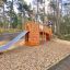 Holz-Spielplatzgerät Schiff Modern Nature mit Rutsche und Kletterelementen in natürlicher Umgebung.