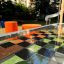 Hpl Bank & Spieltisch mit Schachbrettmuster und orangen Sitzhockern im Außenbereich.