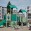 Spielplatzgerät Bastei mit Rutsche aus grünem Kunststoff und Metall, Kinder spielen und klettern dar