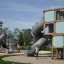 Breezekiste mit Rutsche auf modernem Spielplatz aus Holz und Metall.