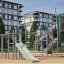 Kinderspielplatz Alpha Centauri mit Rutsche, Klettergerüsten und Tunnelrutsche vor Wohnhäusern.
