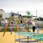 Kinder spielen auf einem Karussell und einer Schaukel auf einem Spielplatz.