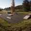 Skatepark mit Curb Sloping in verschiedenen Höhen, umgeben von Gras und Bäumen.