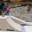 Kinder beim Skateboarden auf einer kleinen Rampe im Freien.