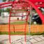 Rotes Klettergerüst Krabbe II mit Hängebrücke und Seil auf einem Spielplatz.