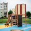 Kinder spielen auf einem Klettergerüst mit Kletterwand und Rutsche auf einem Spielplatz.