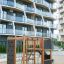 Klettergerüst mit Kletterwand und Rutsche aus Holz auf einem Spielplatz vor Wohngebäuden