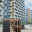 Klettergerüst mit Kletterwand und Rutsche auf einem Spielplatz vor modernen Wohngebäuden