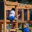 Kinder spielen auf einem Klettergerüst mit Netz, Tunnel und Rutsche im Park.
