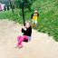 Mädchen lächelt auf der Drahtseilbahn Mittel, Junge im Hintergrund auf dem Spielplatz.
