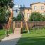Kinderschaukel Drahtseilbahn Mittel auf einem Spielplatz mit grüner Wiese und Stadthintergrund.