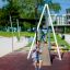 Kind schwingt auf einer Seilbahn auf einem Spielplatz.
