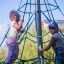 Kinder spielen auf einem Spinnennetz-Kletternetz auf einem Spielplatz.