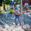 Kind krabbelt auf Spinnennetz-Kletternetz auf Spielplatz.