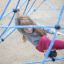 Mädchen klettert auf blauem Spinnennetz-Kletternetz auf Spielplatz.