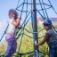Kinder spielen auf einem Spinnennetz-Kletternetz auf einem Spielplatz.