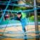 Junge klettert auf einem blauen Spinnennetz – Kletternetz auf Spielplatz.