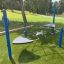 Balancier Spielplatz Netz auf grünem Kunstrasen mit blauen und grauen Elementen im Freien.