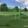 Balancier Spielplatz Netz auf grünem Kunstrasen mit grünen und metallenen Spielgeräten.