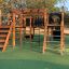 Holzspielgerät Tarzan Klettergerüst mit Tunnel, Rutsche und Kletternetz auf einem Spielplatz.