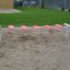 Kinder-Fußgängerbrücke aus rosa Trittflächen und weißen Stangen im Sand.