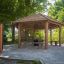 Holzschutzhütte Feuerhaus in einem Park mit Sitzbänken und Tisch.