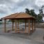 Holz-Pavillon Feuerhaus im Freien auf Kiesboden, umgeben von Bäumen.