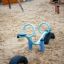 Blauer Wippe aus Gummi und Metall auf einem Spielplatz mit Sandboden.