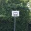 Basketballkorb im Freien vor grünen Bäumen.