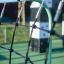 Spielplatzgerät Delphin Kletteranlage mit Netz und grünen Metallstangen auf Spielplatz.
