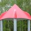 Rotes Dach des Maikäfer Spielturms, umgeben von grünen Bäumen.
