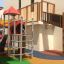 Maikäfer Spielturm mit Kletterwand, Rutsche und Spieltunnel auf einem Spielplatz.